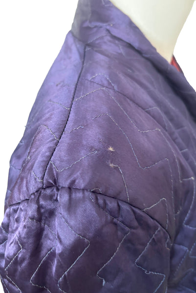 Detail view of 1940s purple satin quilted robe with pink satin lining by Sandora, medium to large. Showing the small hole at the shoulder.