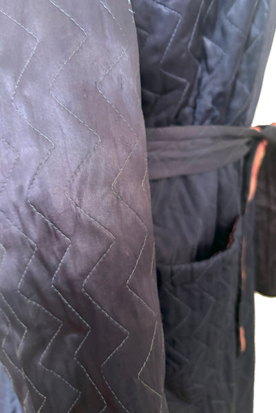 Detail view of 1940s purple satin quilted robe with pink satin lining by Sandora, medium to large. Showing some of the fading.
