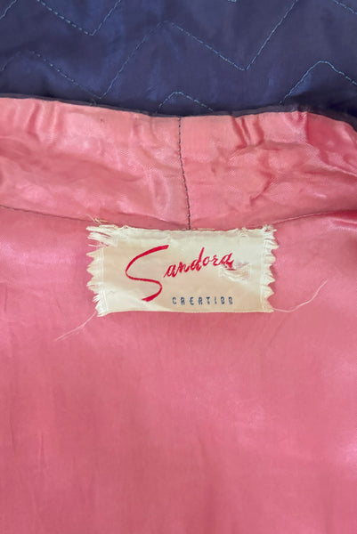Interior detail view of 1940s purple satin quilted robe with pink satin lining by Sandora, medium to large. Showing the Sandora Creation label.