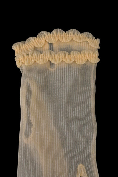 Detail view of 1950s vintage wrist length sheer yellow striped nylon ruffled cuff gloves. Showing a close-up of the double row of matching ruffled trim at the cuff. On a black background.
