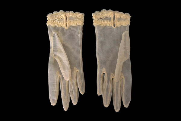 Horizontal back view of 1950s vintage wrist length sheer yellow striped nylon ruffled cuff gloves. On a black background.