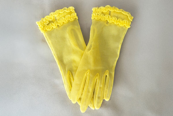 Horizontal pair view of 1950s vintage wrist length sheer yellow striped nylon ruffled cuff gloves. On a gray background.