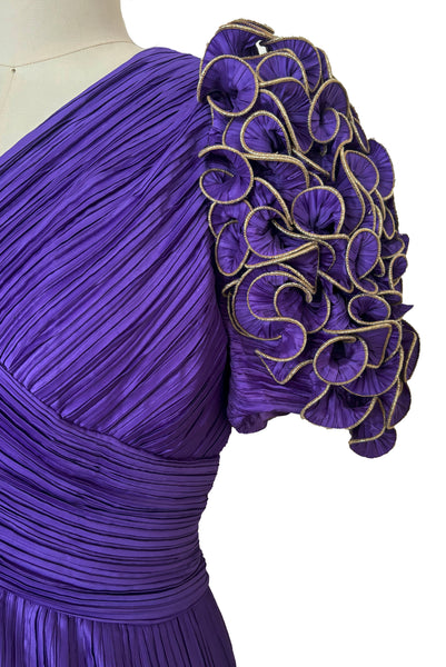 Detail view of 1980s vintage purple peated satin dress with purple and gold ruffled statement sleeves by Richilene, size medium to large. Showing a close-up of the sleeves.