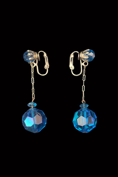 Vertical side view of 1960s vintage blue iridescent crystal and silver chain link top and drop clip on earrings for unpierced ears.