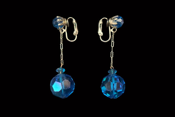 Horizontal side view of 1960s vintage blue iridescent crystal and silver chain link top and drop clip on earrings for unpierced ears.