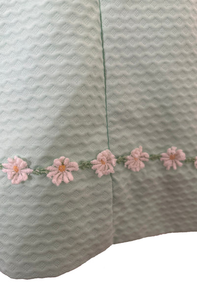 Detail view of 1960s vintage mint green cotton pique daisy trimmed sheath dress, size extra small to small. Showing a close-up of the white, yellow, and green embroidered daisy trim.