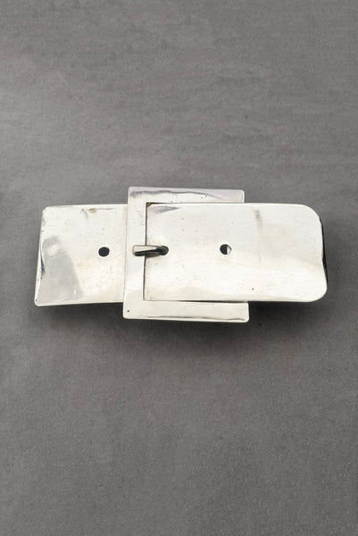 Vertical perspective view of 1980s vintage surrealist silver tone chrome belt buckle shaped novelty buckle.