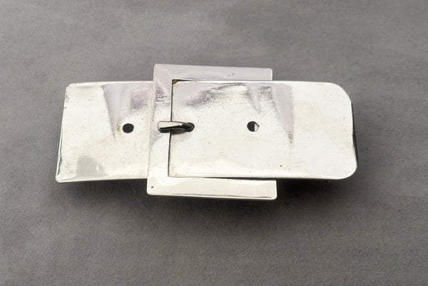 Horizontal perspective view of 1980s vintage surrealist silver tone chrome belt buckle shaped novelty buckle.