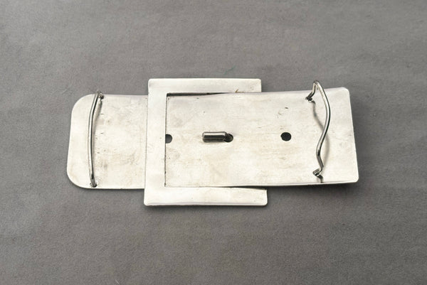 Horizontal back view of 1980s vintage surrealist silver tone chrome belt buckle shaped novelty buckle.