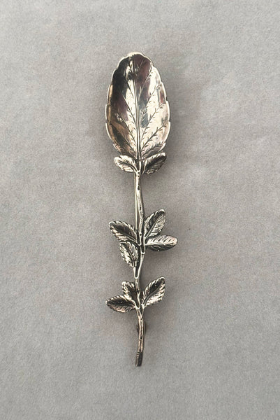 Vertical front view of 1950s vintage silver floral spoon shaped botanical brooch.