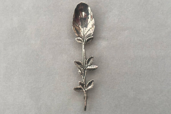 Horizontal front view of 1950s vintage silver floral spoon shaped botanical brooch.