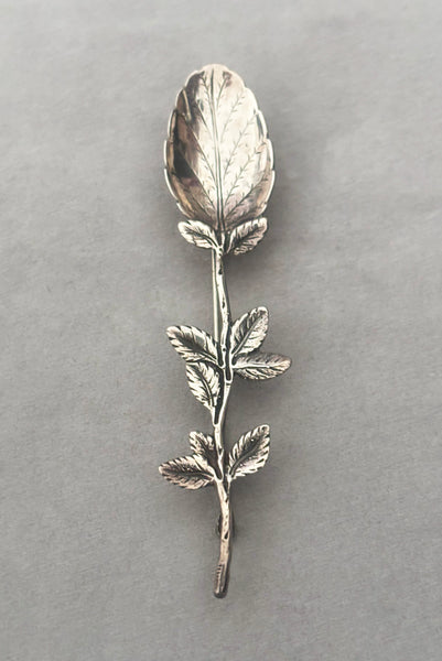 Vertical perspective view of 1950s vintage silver floral spoon shaped botanical brooch.