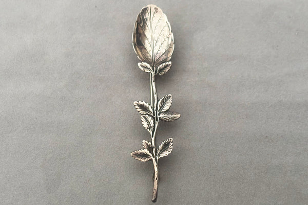 Horizontal perspective view of 1950s vintage silver floral spoon shaped botanical brooch.