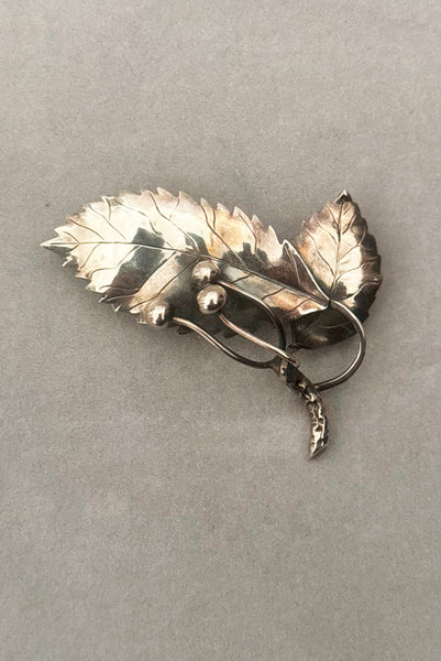 Vertical front view of 1950s vintage Gertrud Engel 925 sterling silver Danish modernist leaf and berry botanical brooch for Anton Michelsen, made in Denmark.