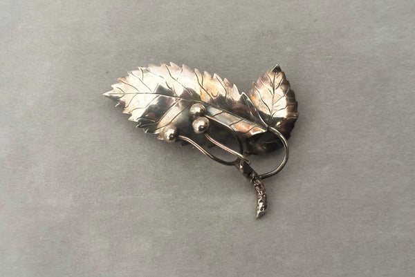 Horizontal front view of 1950s vintage Gertrud Engel 925 sterling silver Danish modernist leaf and berry botanical brooch for Anton Michelsen, made in Denmark.