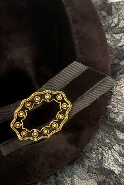 Detail view of 1950s vintage black velvet and lace one size pancake cocktail hat with ribbon and gold tone metal buckle, by Lemington for Frederick & Nelson. Showing a lose up of the petersham and velvet ribbon trim held in place with a gold tone metal buckle. 