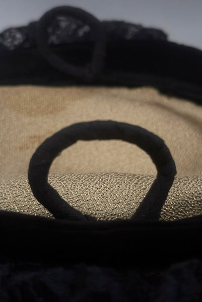 Detail view of 1950s vintage black velvet and lace one size pancake cocktail hat with ribbon and gold tone metal buckle, by Lemington for Frederick & Nelson. Showing a close up of the millinery wire loops covered in black seam binding.