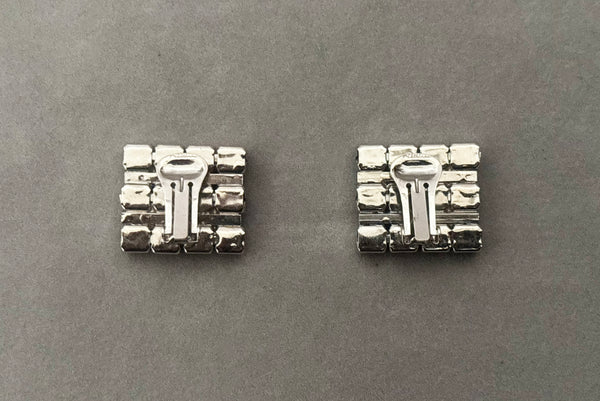 Horizontal back view of 1960s vintage large rectangular silver tone and round emerald green rhinestone clip-on earrings.