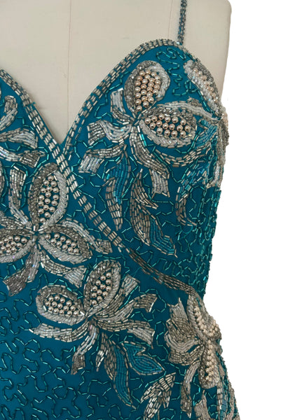 Detail view of 1980s vintage sweetheart neckline turquoise blue asymmetrical fringed beaded cocktail dress, size small to medium. Showing the white and silver floral beading.