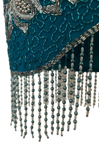 Detail view of 1980s vintage sweetheart neckline turquoise blue asymmetrical fringed beaded cocktail dress, size small to medium. Showing the blue and clear beaded curved fringe hem