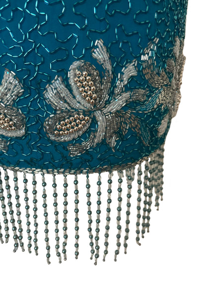 Detail view of 1980s vintage sweetheart neckline turquoise blue asymmetrical fringed beaded cocktail dress, size small to medium. Showing the blue and clear beaded curved fringe hem.