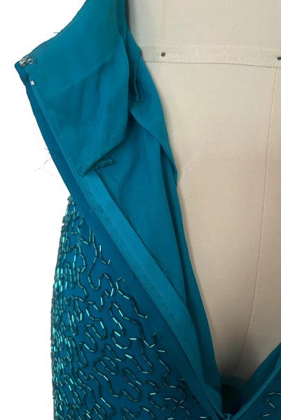 Detail view of 1980s vintage sweetheart neckline turquoise blue asymmetrical fringed beaded cocktail dress, size small to medium. Showing the nylon zipper and turquoise blue synthetic lining.