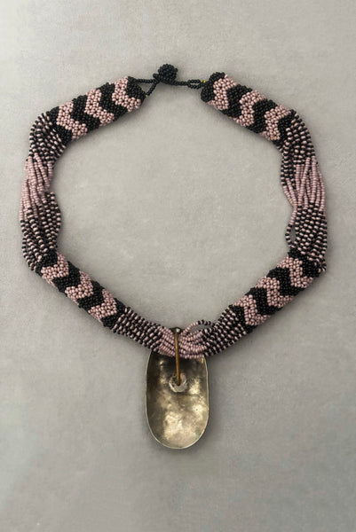 Vertical back view of 1970s vintage black and pale purple seed bead beadwork necklace with silver hammered oval pendant.