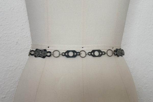 Mannequin back view of 1930s vintage black celluloid and silver tone metal filigree link belt.