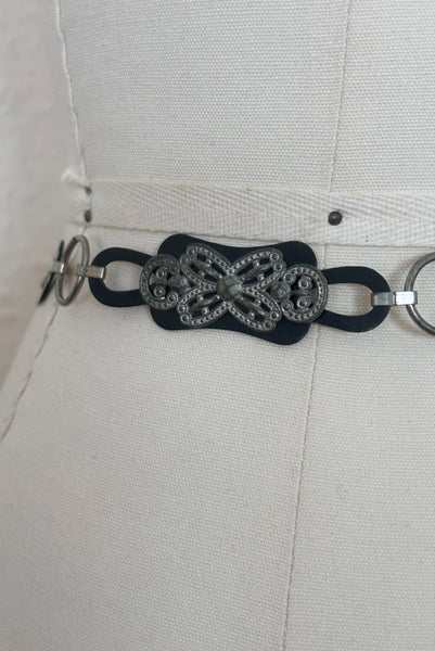 Detail view of 1930s vintage black celluloid and silver tone metal filigree link belt. Showing a close-up of the black celluloid and silver tone metal filigree links.