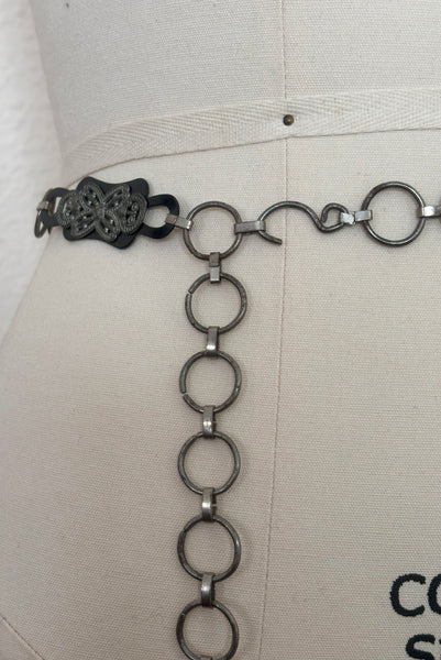Detail view of 1930s vintage black celluloid and silver tone metal filigree link belt. Showing a close-up of the hook closure.