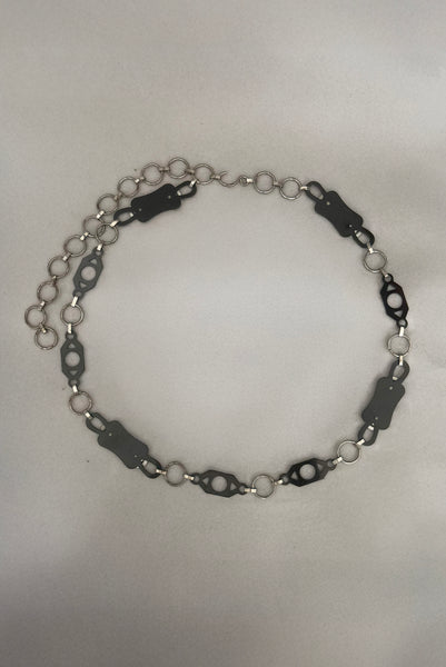 Vertical back view of 1930s vintage black celluloid and silver tone metal filigree link belt.