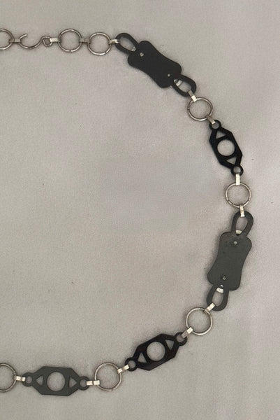 Detail view of 1930s vintage black celluloid and silver tone metal filigree link belt. Showing a close-up of the back of the black celluloid and silver tone metal filigree links.