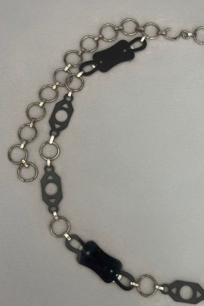 Detail view of 1930s vintage black celluloid and silver tone metal filigree link belt. Showing a close-up of the back of the black celluloid and silver tone metal filigree links.