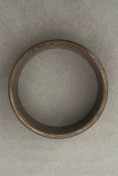 Vertical top view of 1950s vintage gray and brown marbled Lucite plastic sliced bangle bracelet.