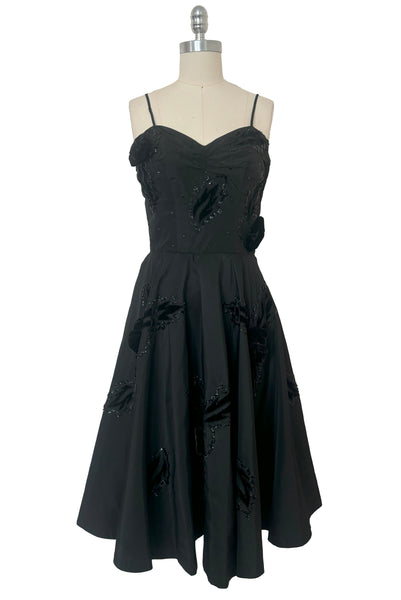 Front view of 1950s vintage black taffeta sequin applique cocktail dress embellished with black velvet roses, size extra extra small to extra small.