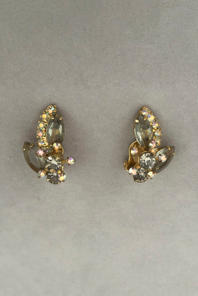 Vertical front view of 1950s vintage gray and iridescent rhinestone gold tone clip-on earrings.