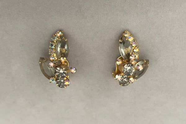 Horizontal front view of 1950s vintage gray and iridescent rhinestone gold tone clip-on earrings.
