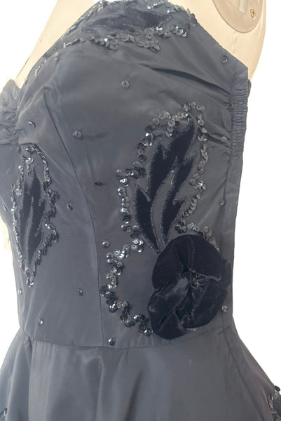Bodice detail view of 1950s vintage black taffeta sequin applique cocktail dress embellished with black velvet roses, size extra extra small to extra small. Showing the black velvet leaf appliques embellished with sequins and 3 dimensional roses.