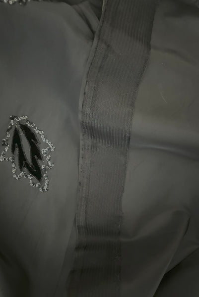 Skirt detail view of 1950s vintage black taffeta sequin applique cocktail dress embellished with black velvet roses, size extra extra small to extra small. Showing the horsehair braid hem 
