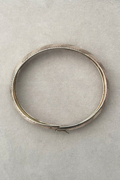 Vertical top view of 1970s vintage stripe engraved Italian 925 sterling silver bangle bracelet made in Salerno, Italy. Showing the slide clasp with hinged latch.