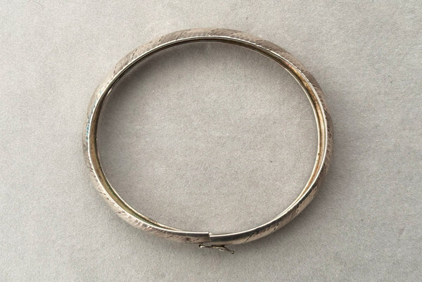 Horizontal top view of 1970s vintage stripe engraved Italian 925 sterling silver bangle bracelet made in Salerno, Italy. Showing the slide clasp with hinged latch.