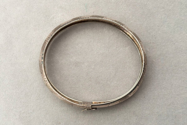 Horizontal top view of 1970s vintage stripe engraved Italian 925 sterling silver bangle bracelet made in Salerno, Italy. Showing the slide clasp with hinged latch.