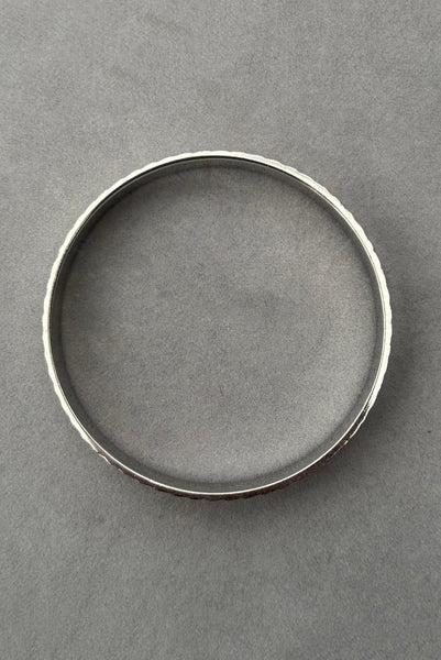 Vertical top view of 1980s vintage petite silver tone chrome engraved bangle bracelet by Monet, size small.
