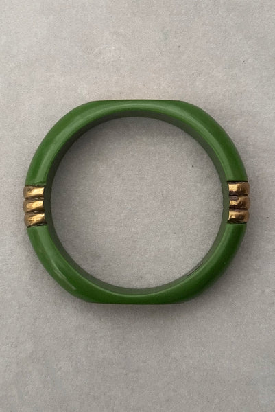 Vertical top view of 1970s vintage green plastic and brass bangle bracelet, made in India.