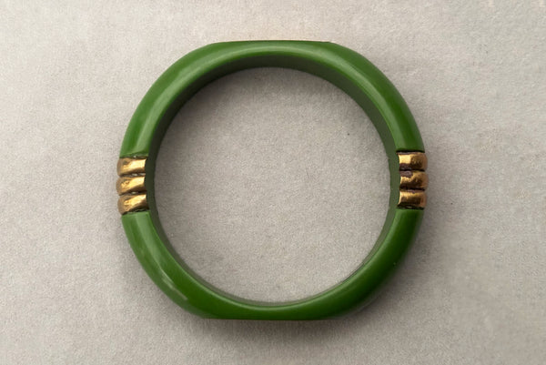 Horizontal top view of 1970s vintage green plastic and brass bangle bracelet, made in India.