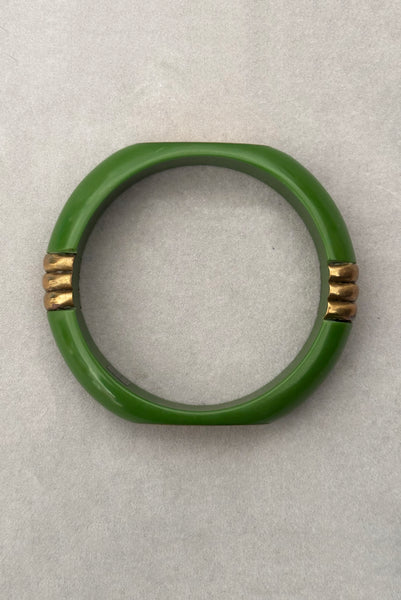 Vertical bottom view of 1970s vintage green plastic and brass bangle bracelet, made in India.