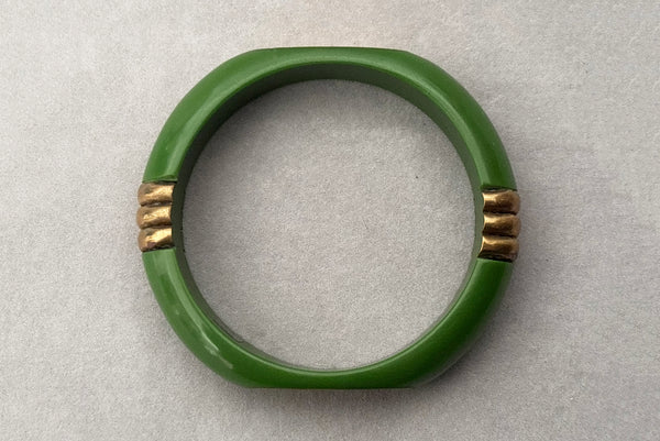 Horizontal bottom view of 1970s vintage green plastic and brass bangle bracelet, made in India.