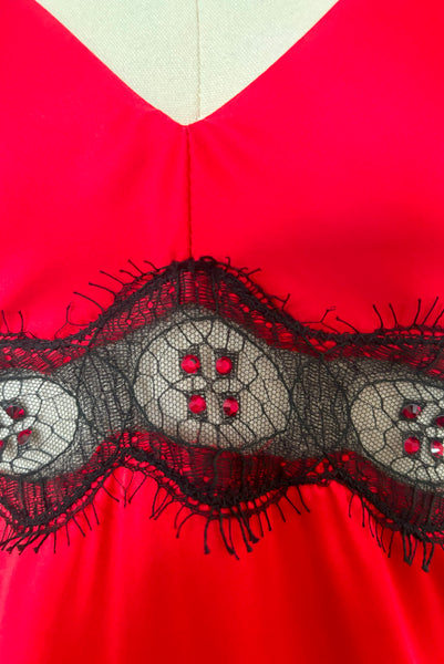 Detail view of new without tags 2000s vintage siren long nightgown in ginger red satin, red rhinestones, and black lace by Spoylt, extra small to small. Showing the black lace trim embellished with red rhinestones at the empire waist.