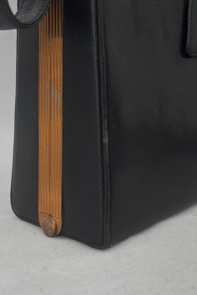 Detail view of 1930s vintage Art Deco black leather gold frame handbag by Evans with coin purse, mirror, comb, and lipstick holder. Showing wear to the edge of the bag and the frame.