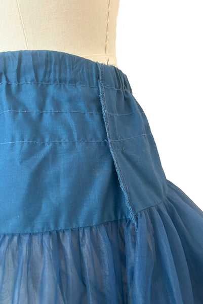 Detail view of 1970s vintage dark blue nylon adjustable petticoat by Malco Modes, small, medium, large. Showing the elastic waist and serged seam on the exterior so it is covered by the dress when worn.